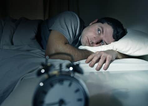  man in bed with eyes opened suffering insomnia and sleep disorder 