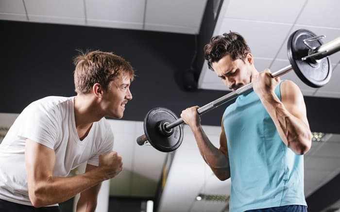 Young man motivating gym buddy during bicep exercise Young man motivating gym buddy during bicep exercise